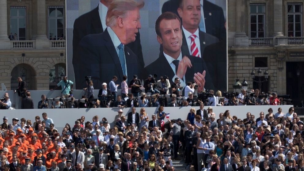 ARCHIVO - El presidente estadounidense Donald Trump --en la pantalla a la izquierda--, el mandatario frances Emmanuel Macron y el jefe de despacho de la Casa Blanca, Reince Priebus, --atrás a la derecha-- observan un desfile por el Día de la Bastilla sobr