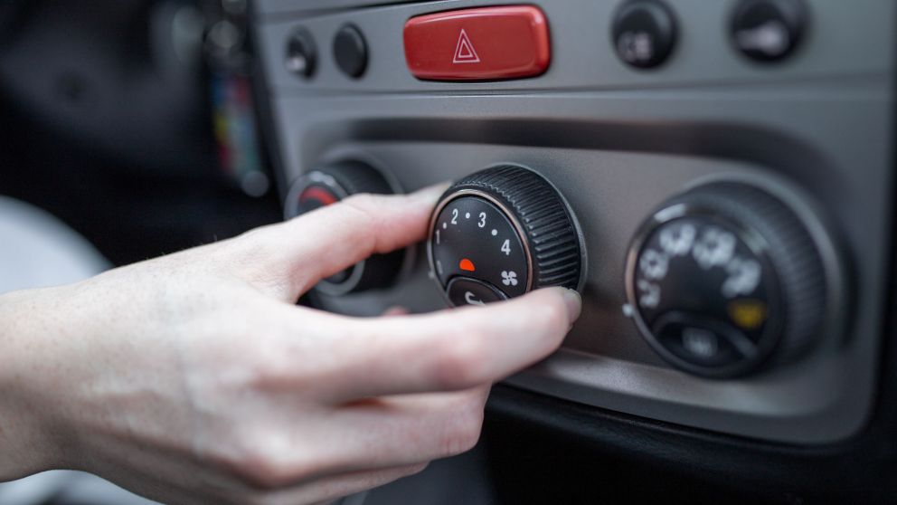 Woman hand turning on car air conditioning system, car air conditioner on off button close up view