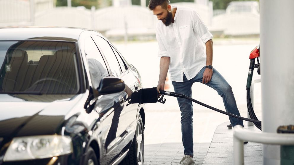 Man on a gas station. Guy refuelong a car. Male in a white shirt.