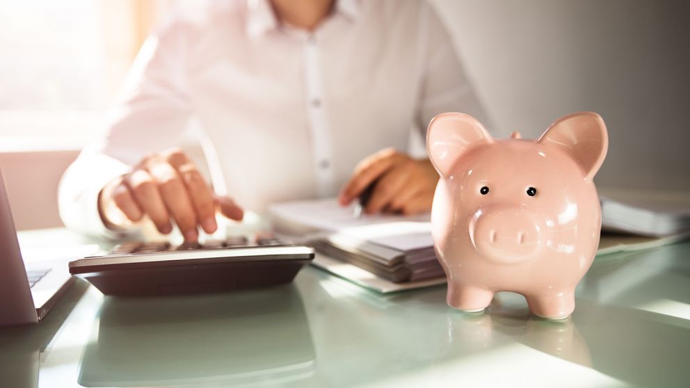Close-up of a piggybank in front of businessman calculating bill with calculator