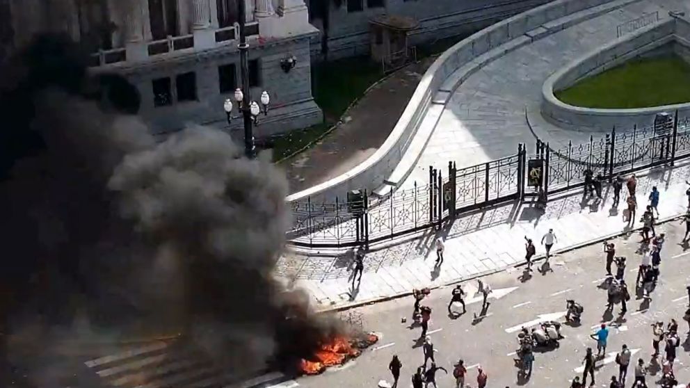 El momento en el que los atacantes lanzan los piedrazos, luego de quemar neumáticos frente al Congreso