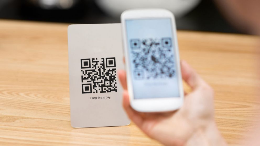 Closeup of a hand holding phone and scanning qr code. Woman hand paying with qr code. Close up of customer hand making payment through smart phone and scan code.
