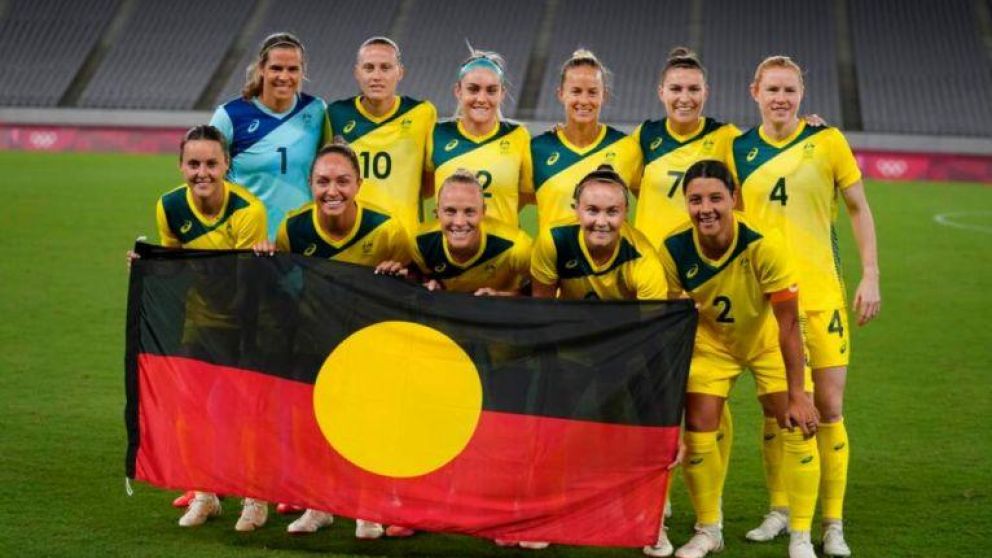 El equipo de fútbol femenino de Australia luciendo una bandera indígena