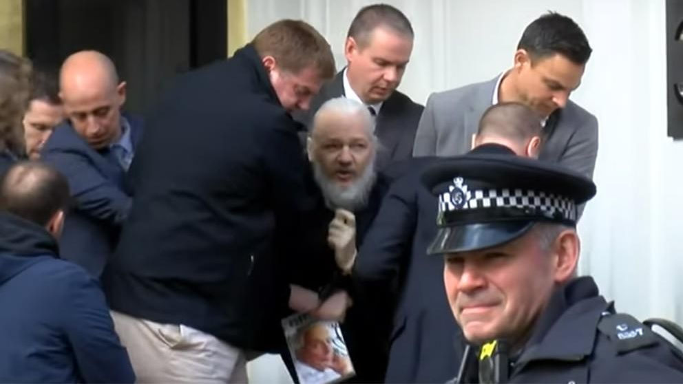 Assange, de barba blanca y visiblemente deteriorado.